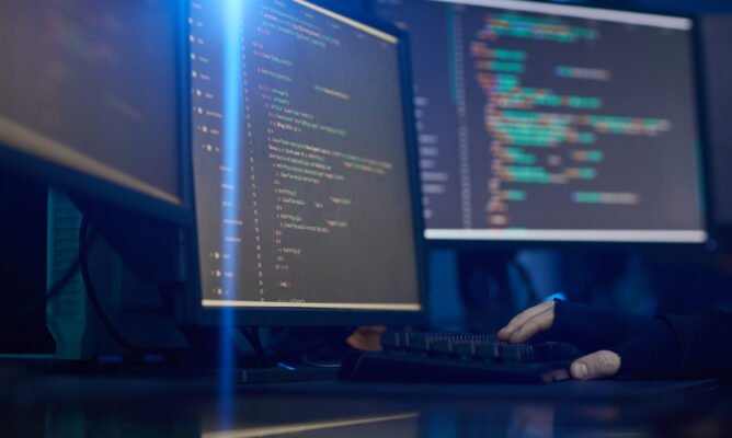 Image of computer monitors with software standing on the table in dark office